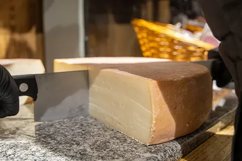 Découpe d’un fromage de Savoie dans l’épicerie Au Petit Terroir à Annecy